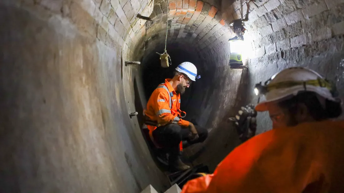 Geosurv technician inspecting the inside of a large brick stormwater tunnel